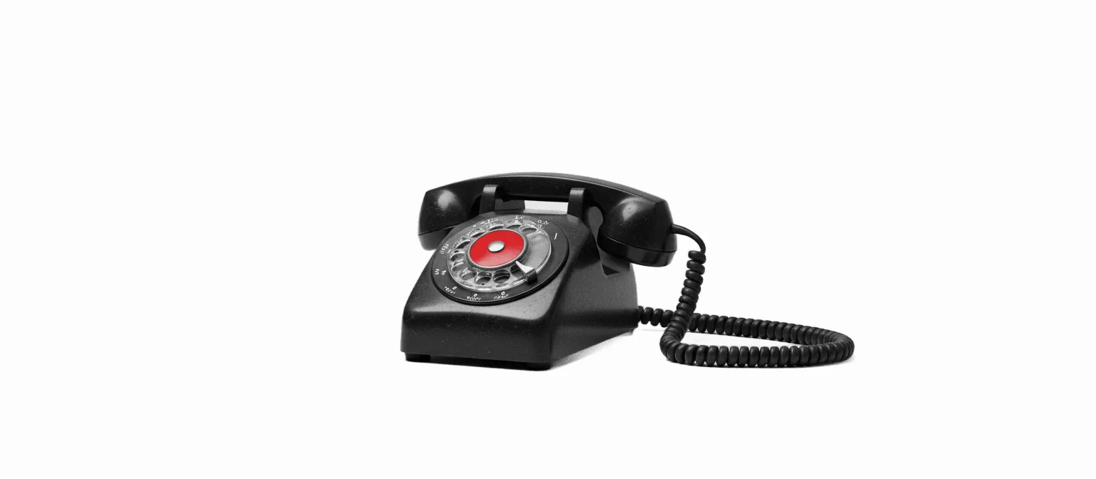 Vintage rotary desk telephone with red-glowing dial — Automaton Agency's build-vs-buy AI receptionist guide for small businesses.