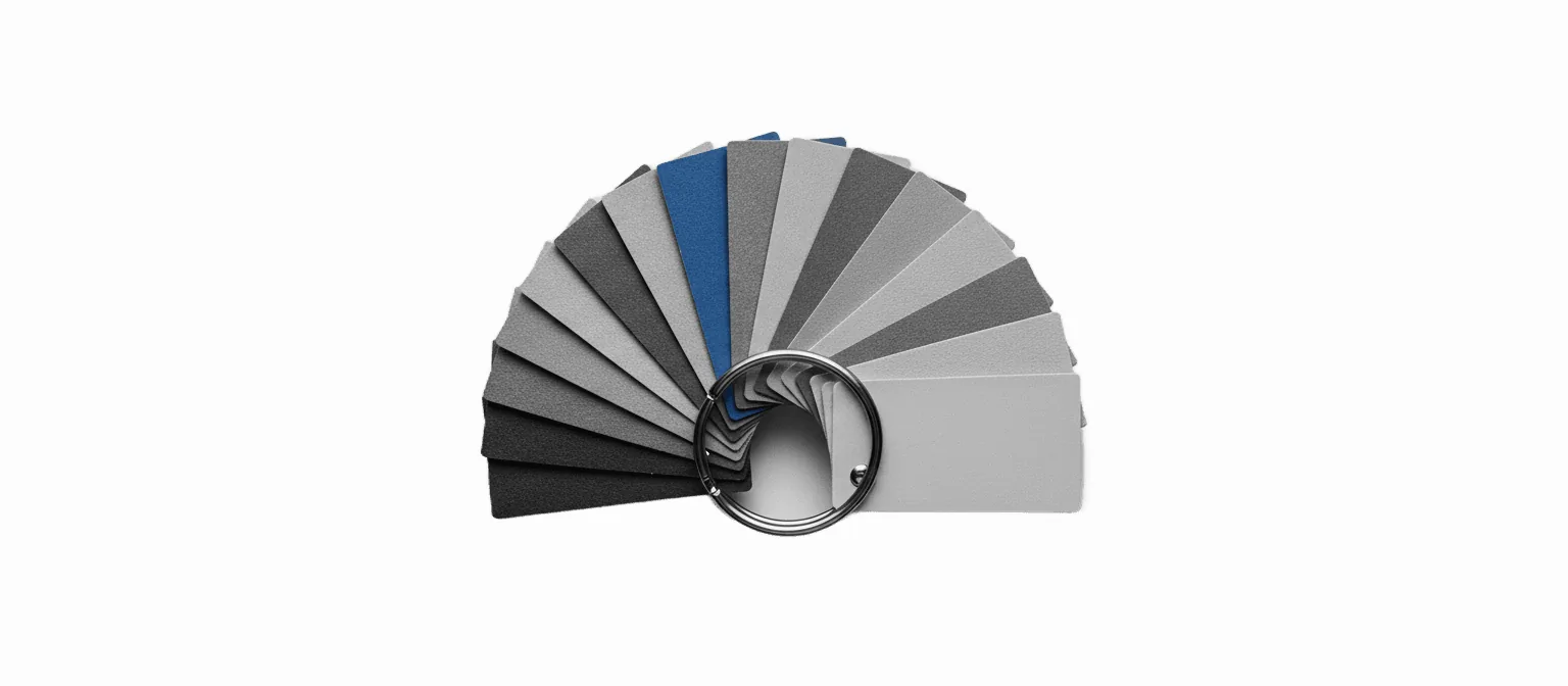A metal ring of fanned material swatch samples in greyscale with one swatch in vivid blue, on a white background