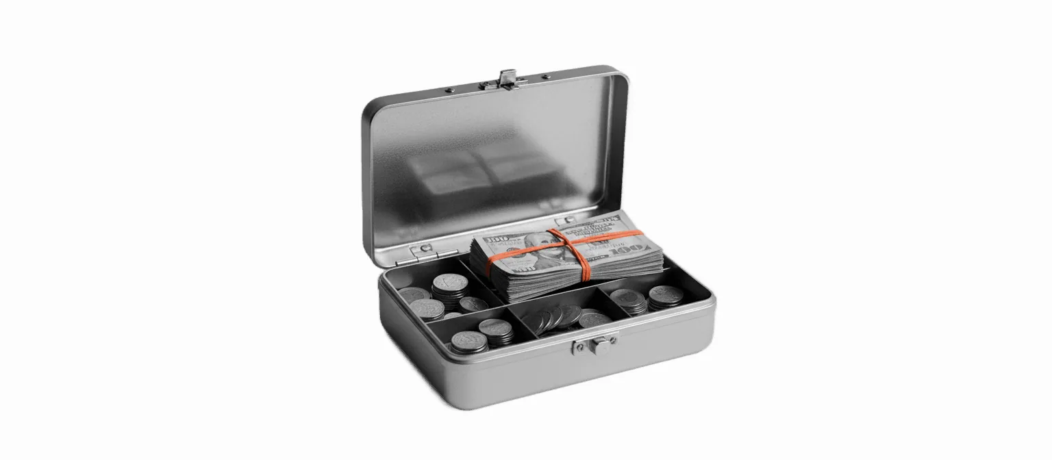 Black-and-white photograph of a small grey metal cash box of the kind used at school fundraisers, lid open showing a tray with folded bills and stacked coins, one bundle wrapped with a vivid coral-orange rubber band