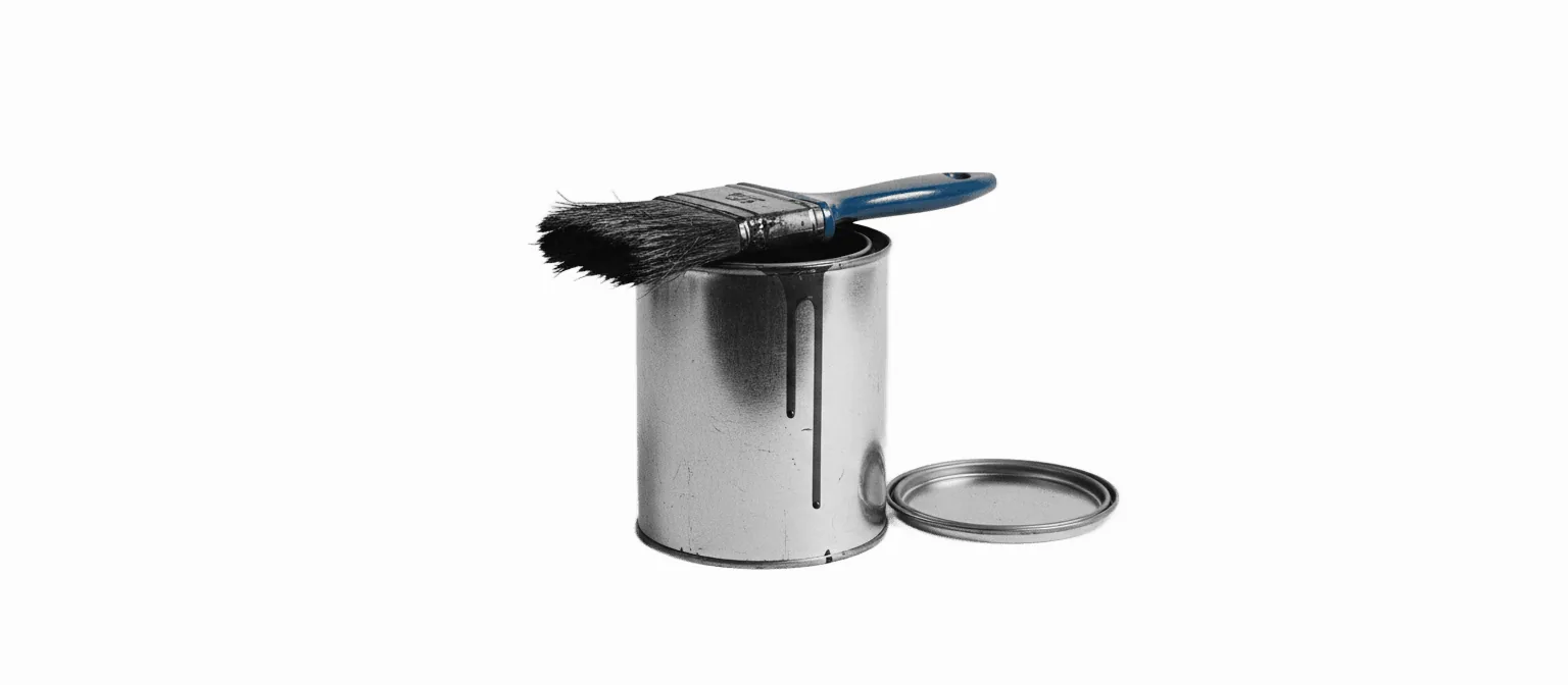 A black-and-white photograph of an open can of wood varnish with a used, varnish-stained brush laid across the rim, drips down the side, and a single blue brush handle as the only color in the frame.